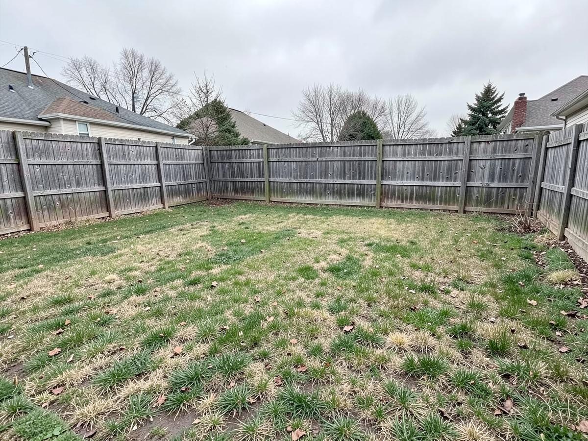 Empty backyard with patchy grass and an aging wood fence before construction